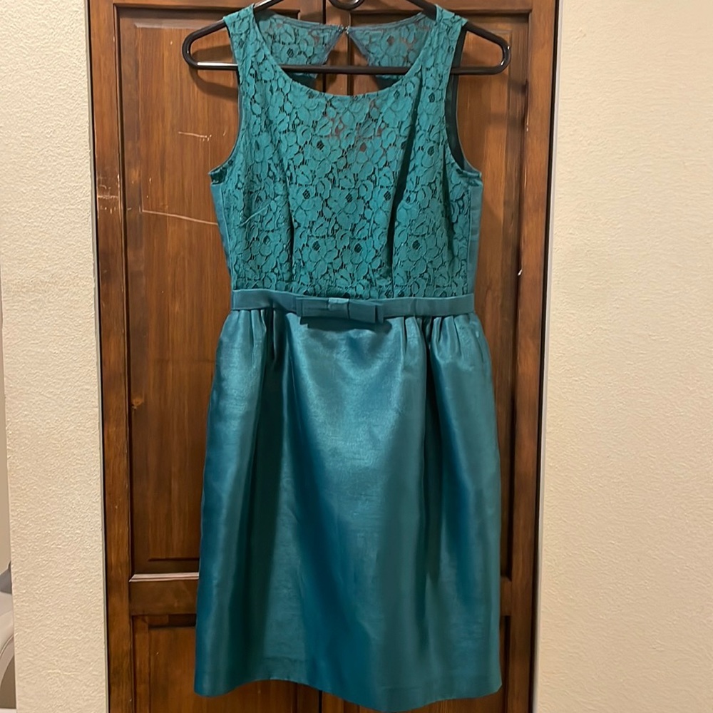 A dark green mini dress with a lace chest along with a bow at the waist